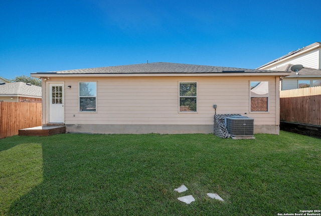 back of property featuring central AC and a lawn