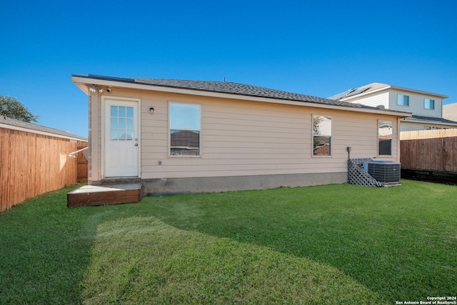 back of property with a yard and central AC