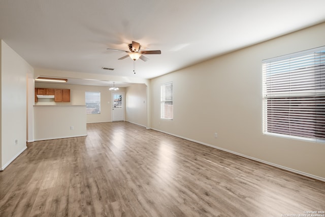 unfurnished living room featuring light hardwood / wood-style floors and ceiling fan with notable chandelier