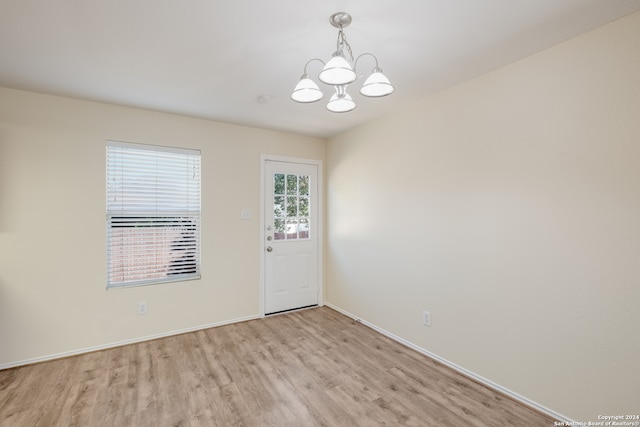 unfurnished room featuring light wood-type flooring and an inviting chandelier