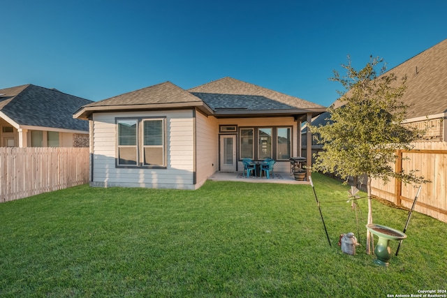 back of house with a lawn and a patio