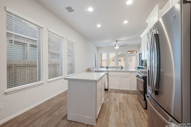 kitchen with white cabinets, light wood-type flooring, stainless steel appliances, and kitchen peninsula