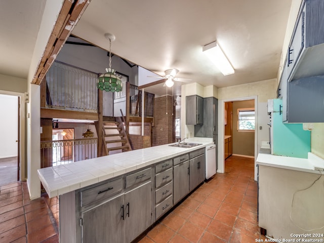 kitchen with ceiling fan, tile counters, sink, kitchen peninsula, and dishwashing machine