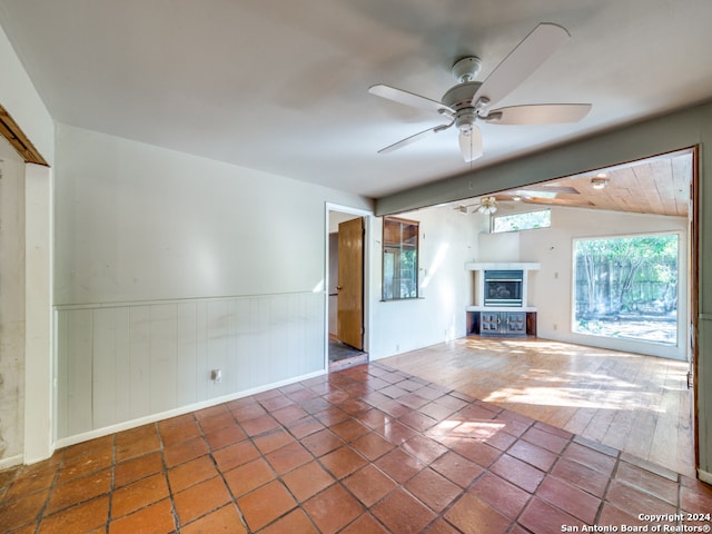 unfurnished living room featuring lofted ceiling with beams, ceiling fan, and dark wood-type flooring