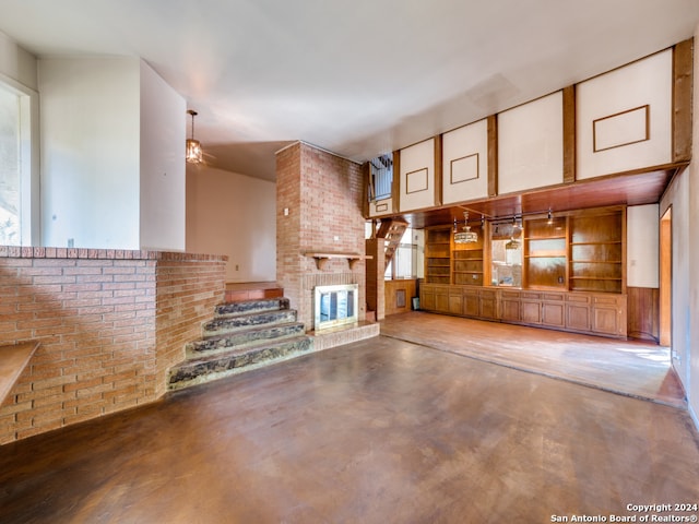 unfurnished living room with concrete floors, a brick fireplace, ceiling fan, and brick wall