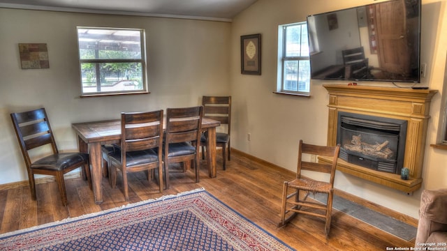 297 Bluff Creek Rd, Leakey, TX 78873 - dining room with wood finished floors, a glass covered fireplace, baseboards, and vaulted ceiling