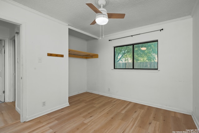 interior space featuring ceiling fan, light hardwood / wood-style floors, a textured ceiling, and ornamental molding