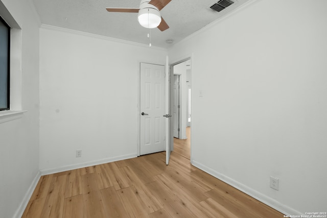 unfurnished room featuring crown molding, ceiling fan, light hardwood / wood-style floors, and a textured ceiling