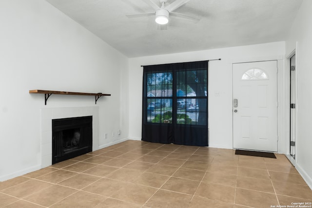 tiled entrance foyer with a textured ceiling, ceiling fan, and a fireplace