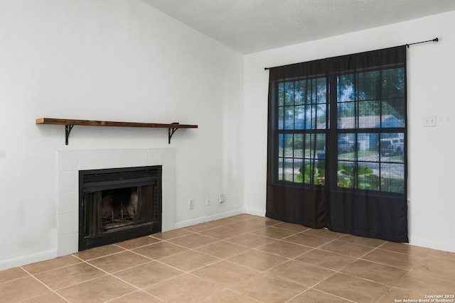 unfurnished living room featuring light tile patterned flooring, a textured ceiling, and a tiled fireplace