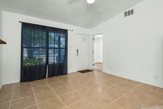 entryway featuring a textured ceiling, ceiling fan, lofted ceiling, and light tile patterned flooring