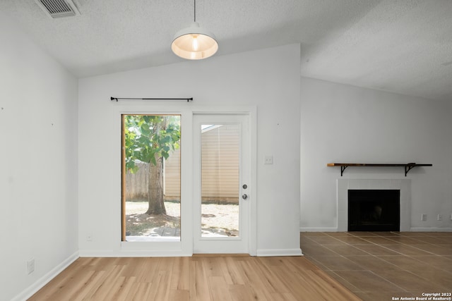 entryway with a tiled fireplace, a wealth of natural light, light hardwood / wood-style flooring, and lofted ceiling