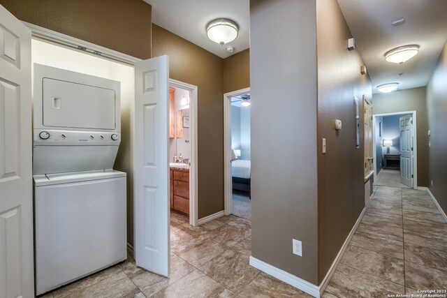 washroom with ceiling fan, sink, and stacked washer / dryer