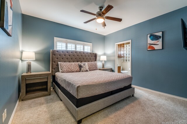 carpeted bedroom with ensuite bath and ceiling fan