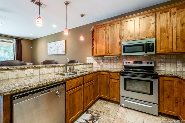 kitchen featuring kitchen peninsula, tasteful backsplash, stainless steel appliances, sink, and decorative light fixtures