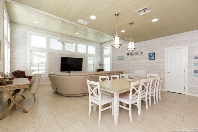 dining room featuring wooden walls, ceiling fan, wooden ceiling, and a wealth of natural light