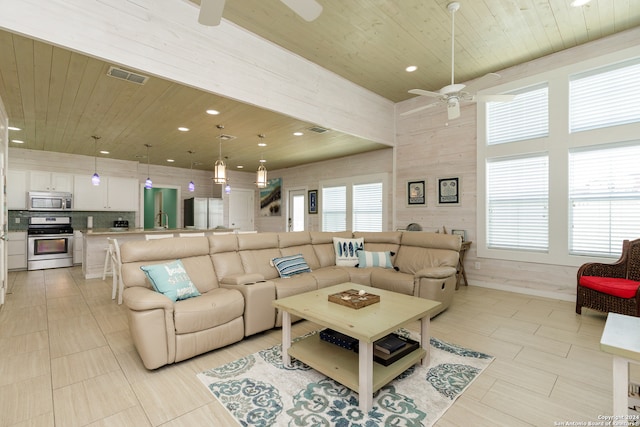 living room with plenty of natural light, ceiling fan, wood ceiling, and sink