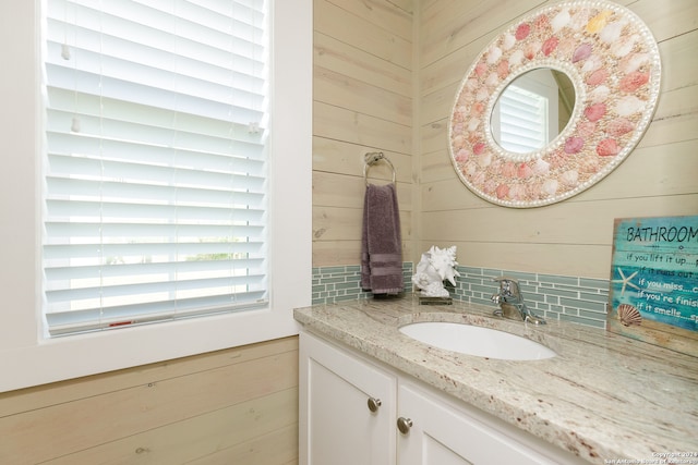 bathroom featuring vanity, decorative backsplash, and wooden walls