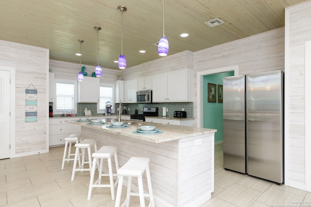 kitchen featuring appliances with stainless steel finishes, a center island, white cabinets, and wooden walls