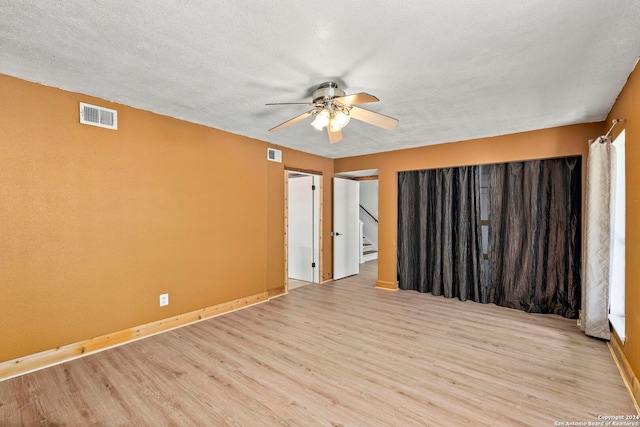 unfurnished room featuring a textured ceiling, light hardwood / wood-style flooring, and ceiling fan