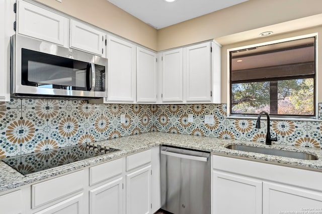 kitchen featuring sink, decorative backsplash, light stone countertops, white cabinetry, and stainless steel appliances