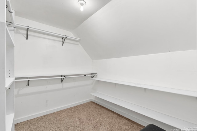 spacious closet featuring light colored carpet and vaulted ceiling