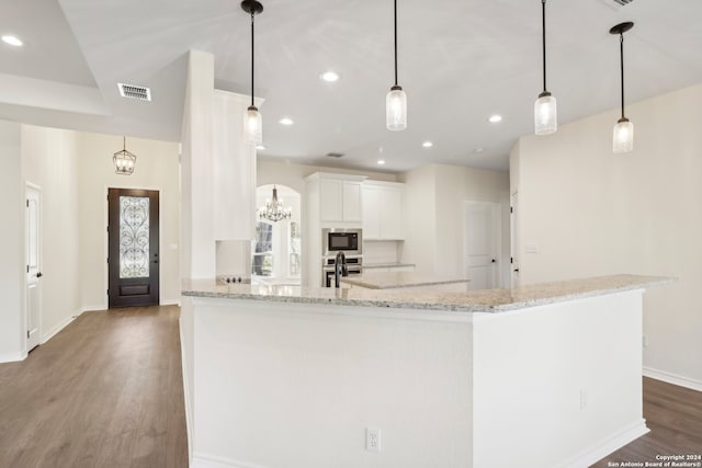 kitchen featuring white cabinets, light stone countertops, appliances with stainless steel finishes, decorative light fixtures, and dark hardwood / wood-style flooring