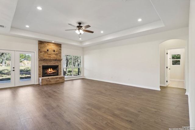 unfurnished living room with dark hardwood / wood-style floors, french doors, a fireplace, and a tray ceiling