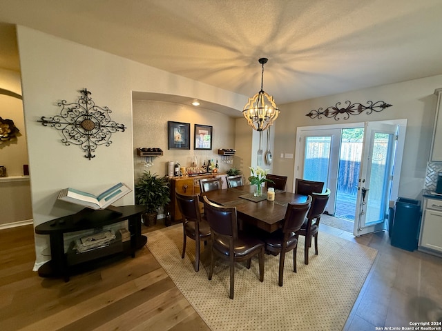 dining area with hardwood / wood-style floors, french doors, and a notable chandelier