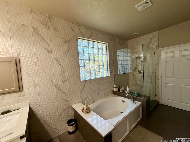 bathroom featuring a textured ceiling, vanity, tile walls, and plus walk in shower