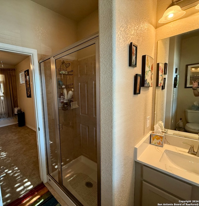 bathroom featuring vanity, toilet, and a shower with shower door