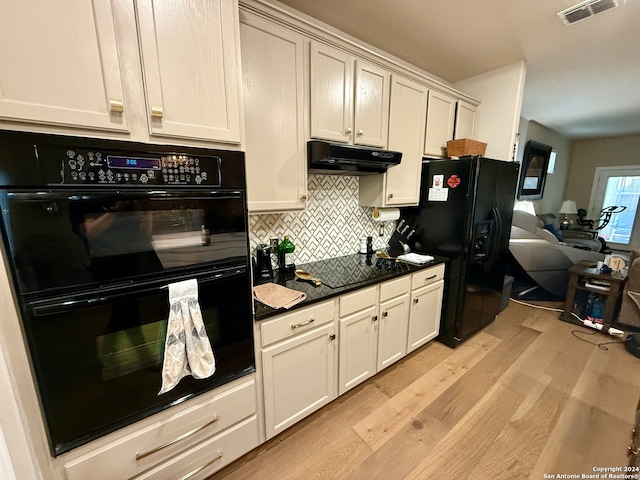 kitchen with decorative backsplash, light wood-type flooring, dark stone counters, and black appliances