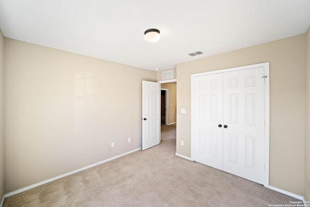 unfurnished bedroom with light carpet and a closet