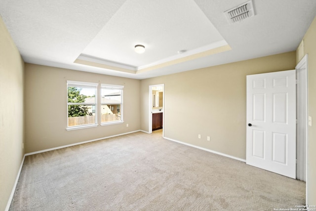 carpeted spare room with a tray ceiling