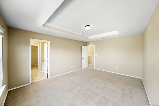 unfurnished bedroom with light colored carpet and a raised ceiling