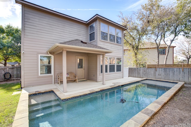 rear view of house featuring a patio and a fenced in pool