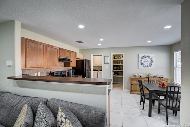 kitchen featuring built in shelves, stainless steel appliances, tasteful backsplash, washing machine and dryer, and kitchen peninsula