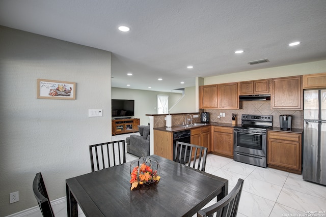 kitchen featuring tasteful backsplash, kitchen peninsula, sink, and appliances with stainless steel finishes