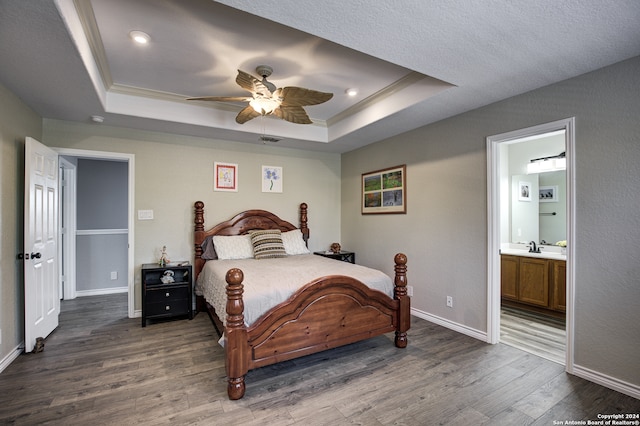 bedroom featuring ceiling fan, a raised ceiling, dark wood-type flooring, and ensuite bath