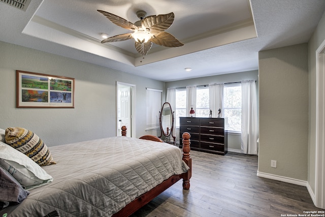 bedroom featuring hardwood / wood-style flooring, ceiling fan, and a raised ceiling