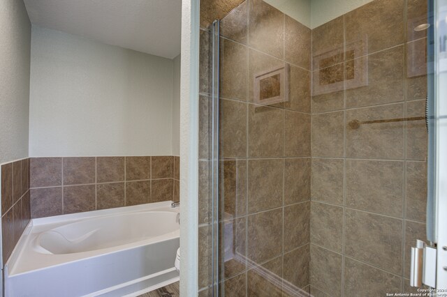 bathroom featuring plus walk in shower, a textured ceiling, and toilet