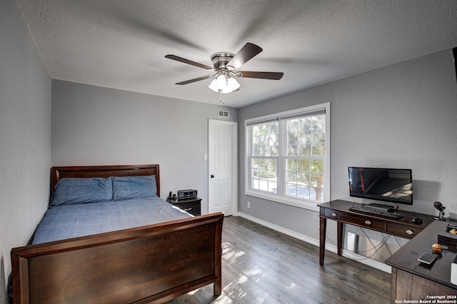 bedroom with a textured ceiling, ceiling fan, and dark wood-type flooring