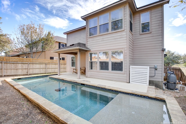 rear view of property featuring a fenced in pool and a patio area