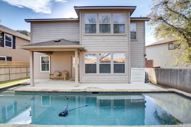 back of property with a fenced in pool and a patio area