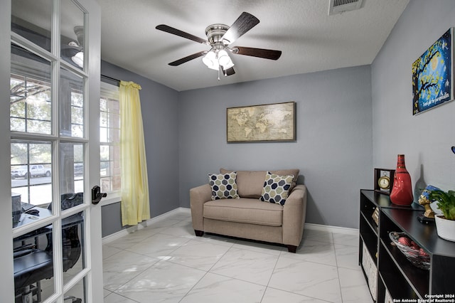 living area with a textured ceiling and ceiling fan