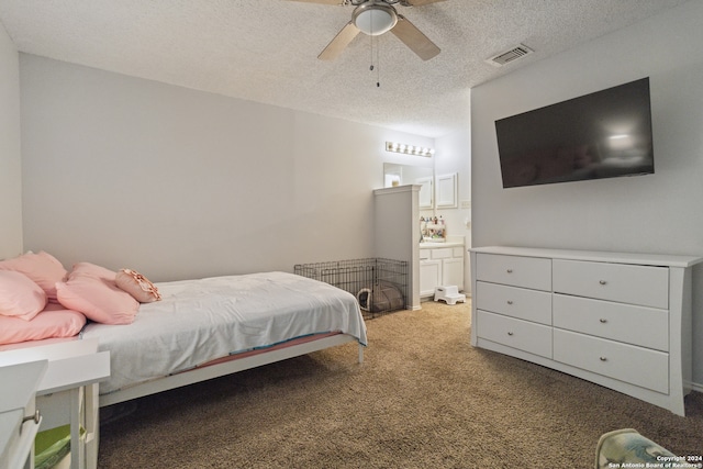 bedroom with carpet flooring, a textured ceiling, ensuite bathroom, and ceiling fan