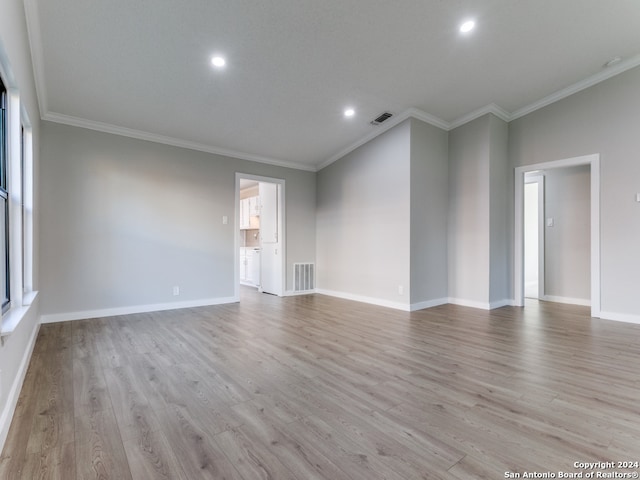 empty room with light hardwood / wood-style floors and crown molding