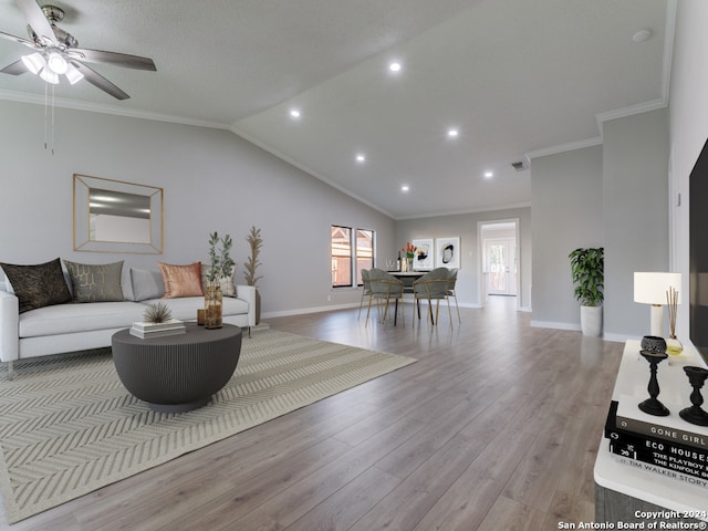 living room featuring lofted ceiling, ceiling fan, light wood-type flooring, and ornamental molding