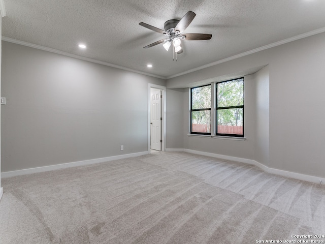 carpeted spare room with ceiling fan, ornamental molding, and a textured ceiling