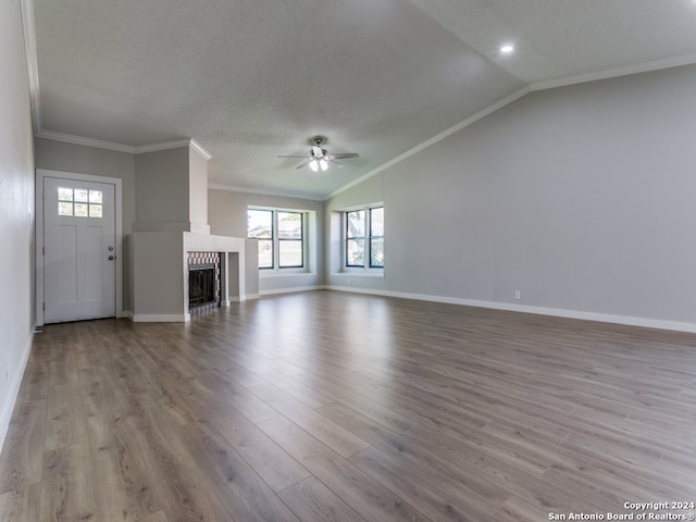 unfurnished living room featuring crown molding, vaulted ceiling, light hardwood / wood-style flooring, ceiling fan, and a fireplace